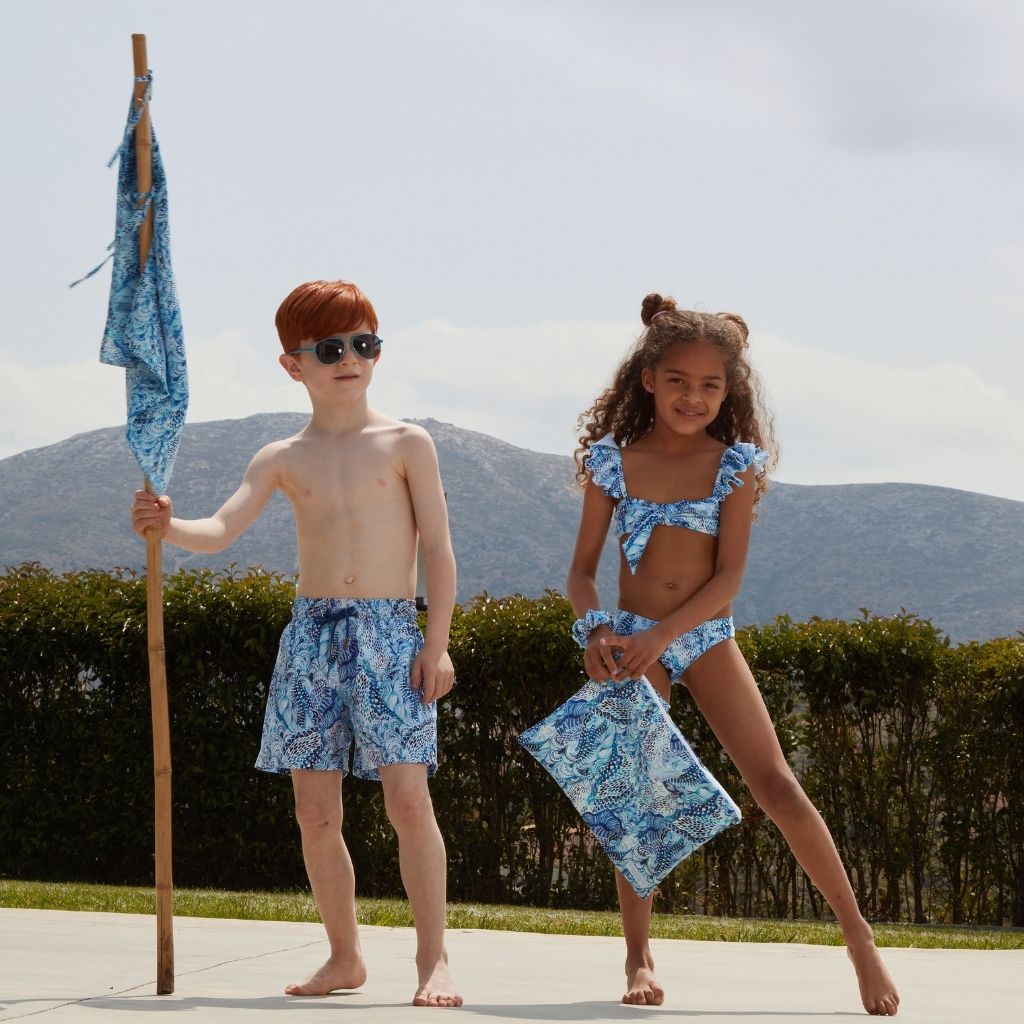 Little girl and boy poolside carrying the Marie Raxevsky large waterproof pouch in wave print