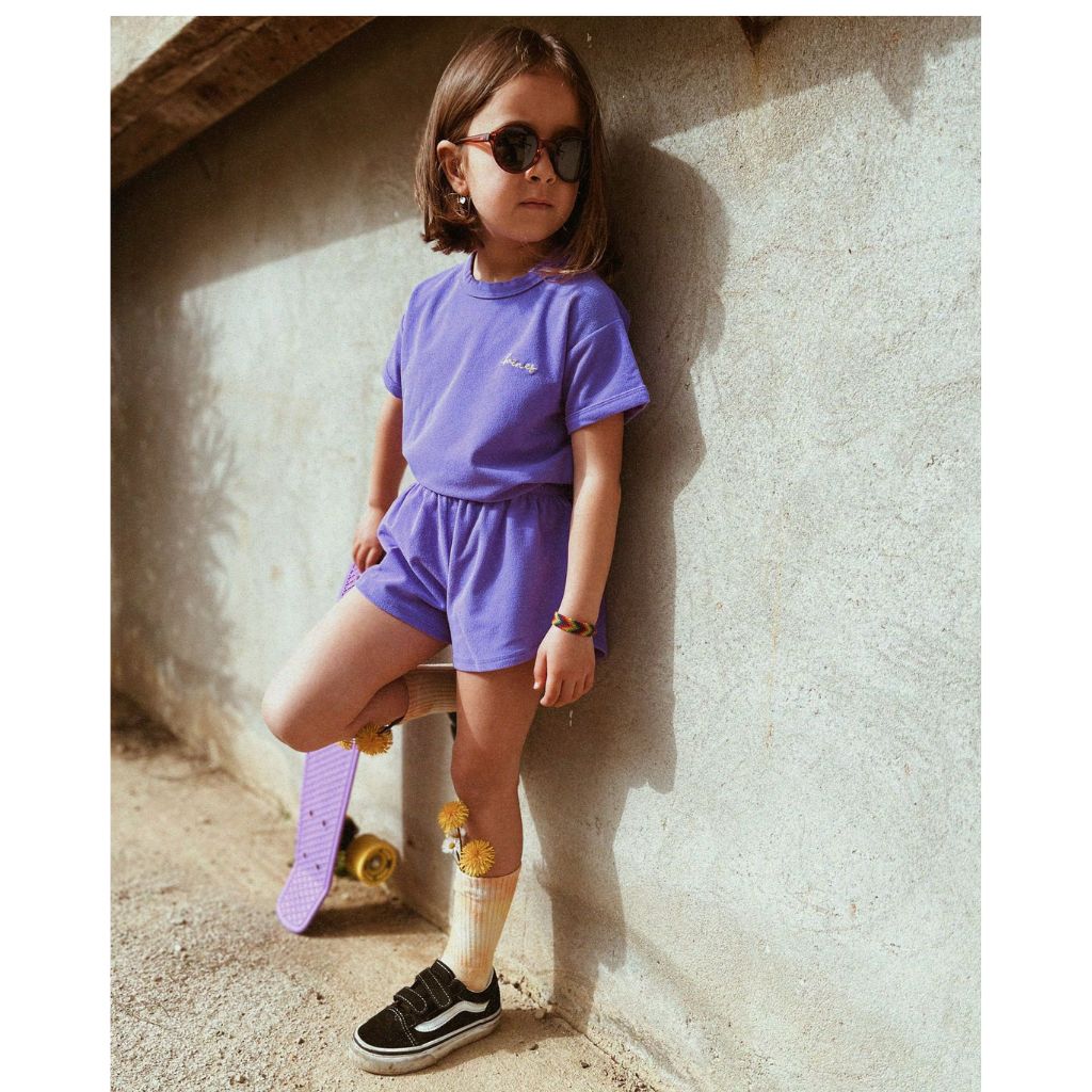 Little girl with her skateboard wearing the Mike beachwear set in blueberry from Baines Collection