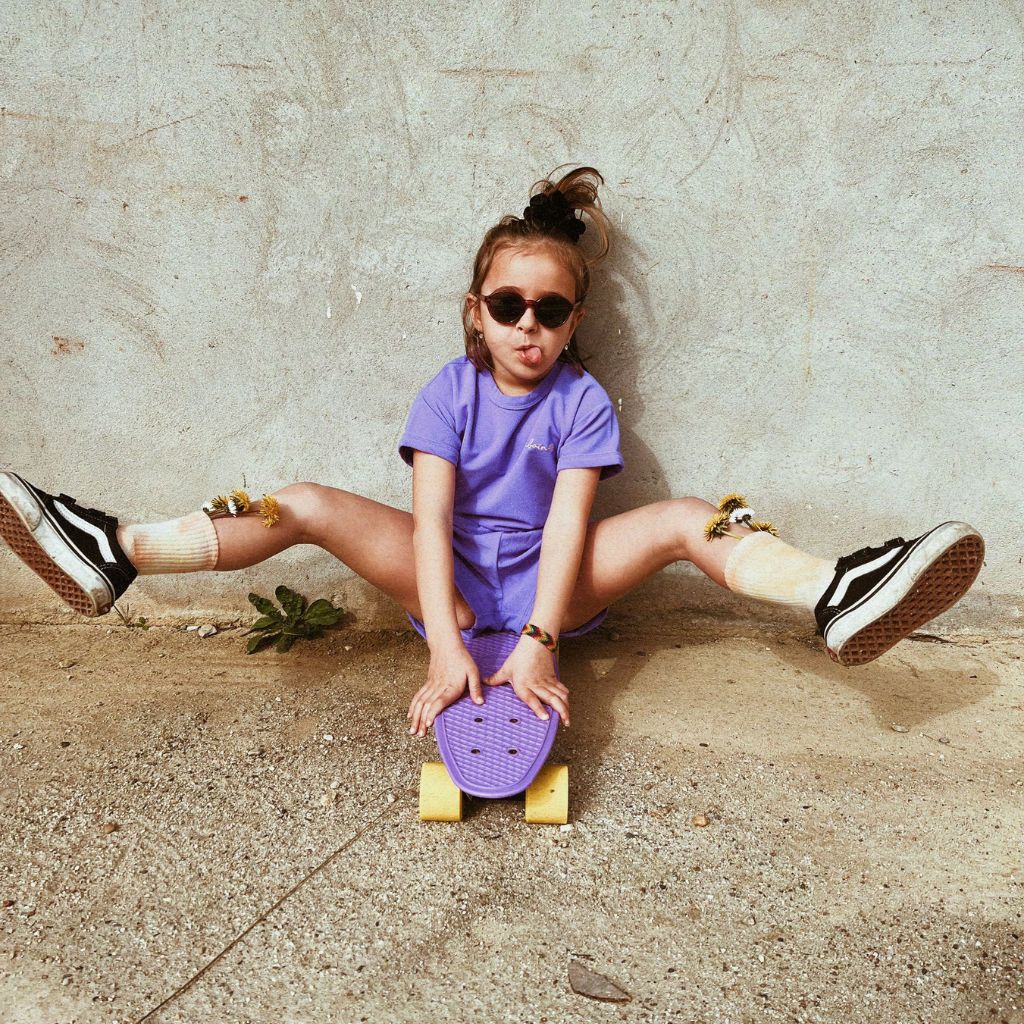 Little girl with her tongue out wearing the Mike beachwear set in blueberry from Baines Collection