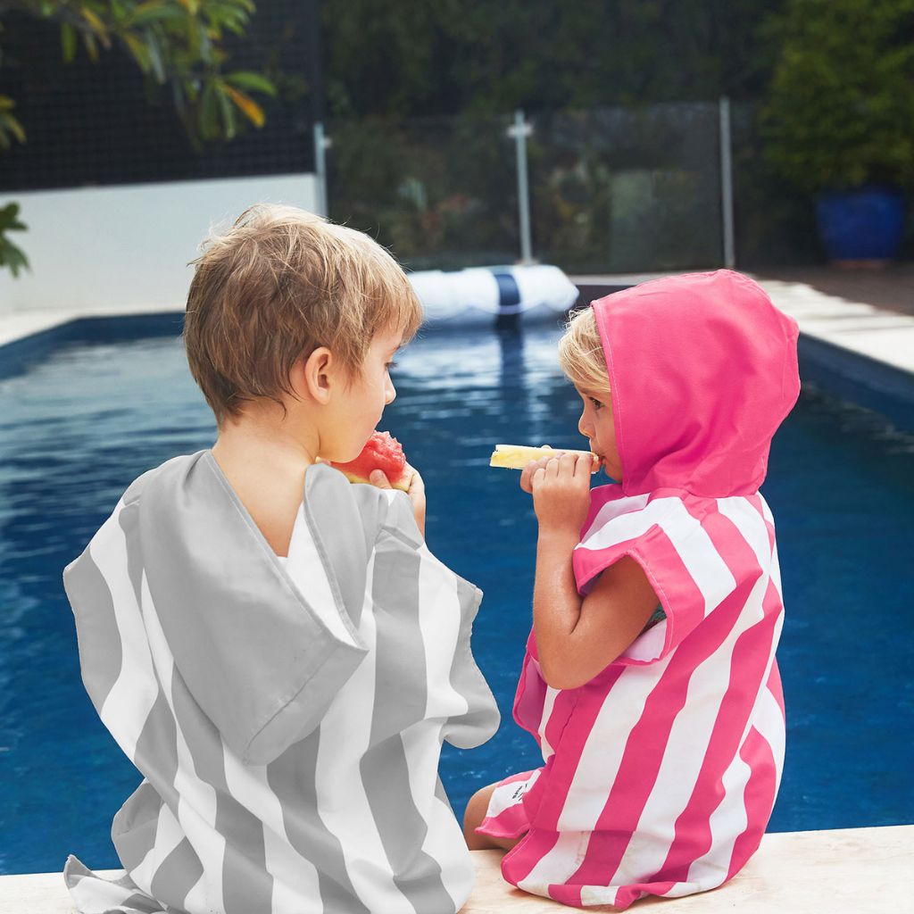 Children by the pool wearing Dock and Bay kids hooded poncho in grey and pink
