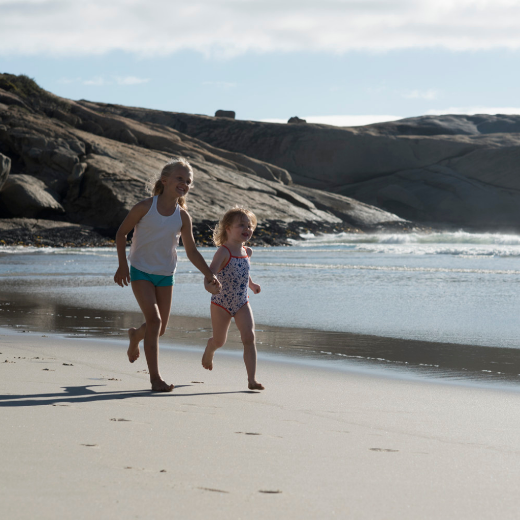 Two little girls running on the beach wearing Evy Technology sunscreen mousse in SPF 30