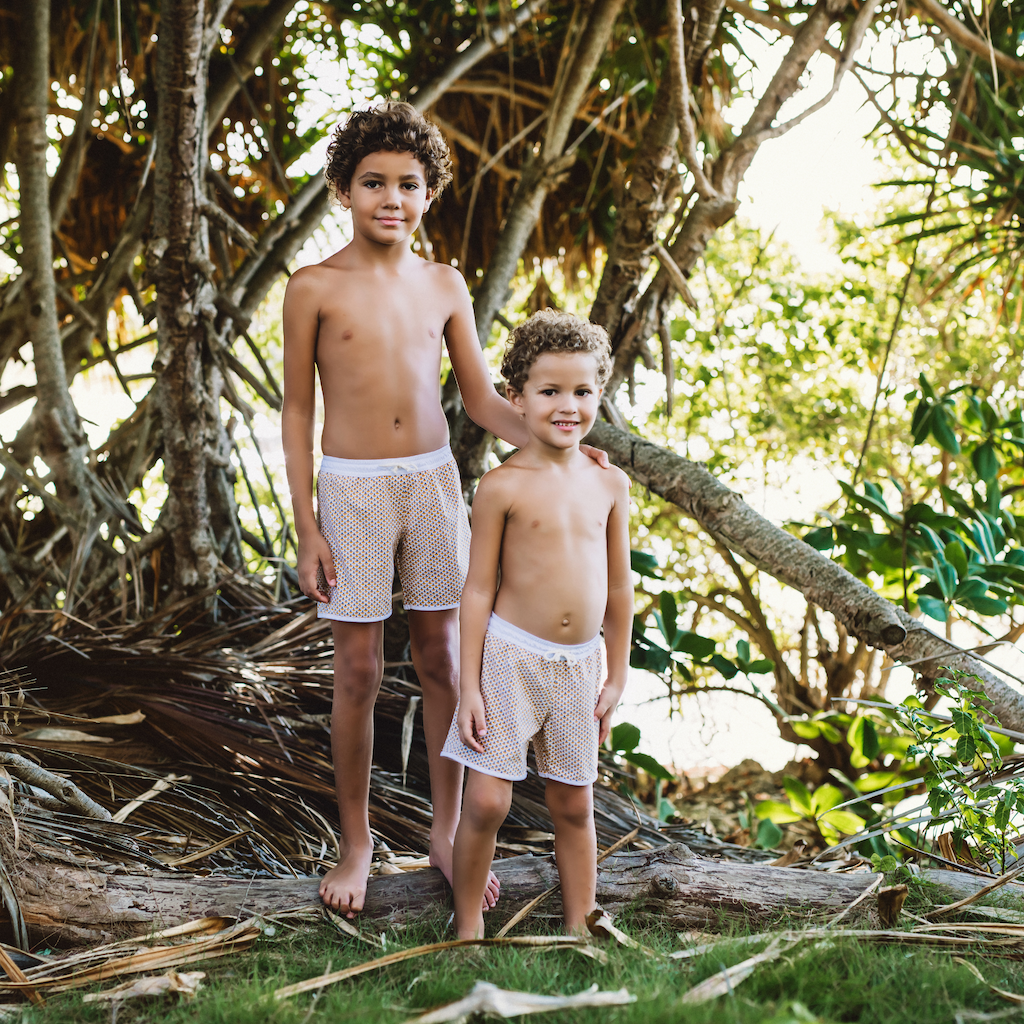 Boys wearing Folpetto Tommaso swim shorts for boys in mango yellow and pebble grey scales print