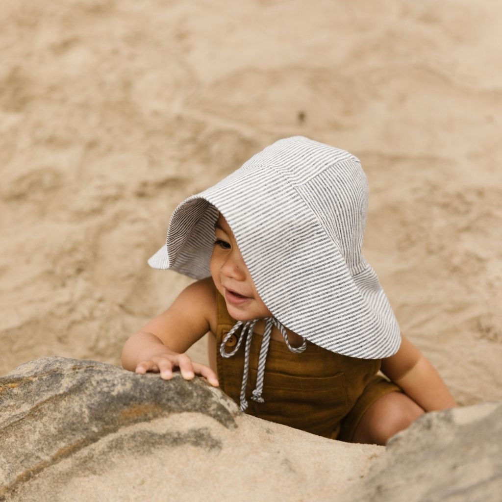 Cute little boy wearing Unisex 100% linen baby sun bonnet from Briar Baby in navy and White Island Stripe