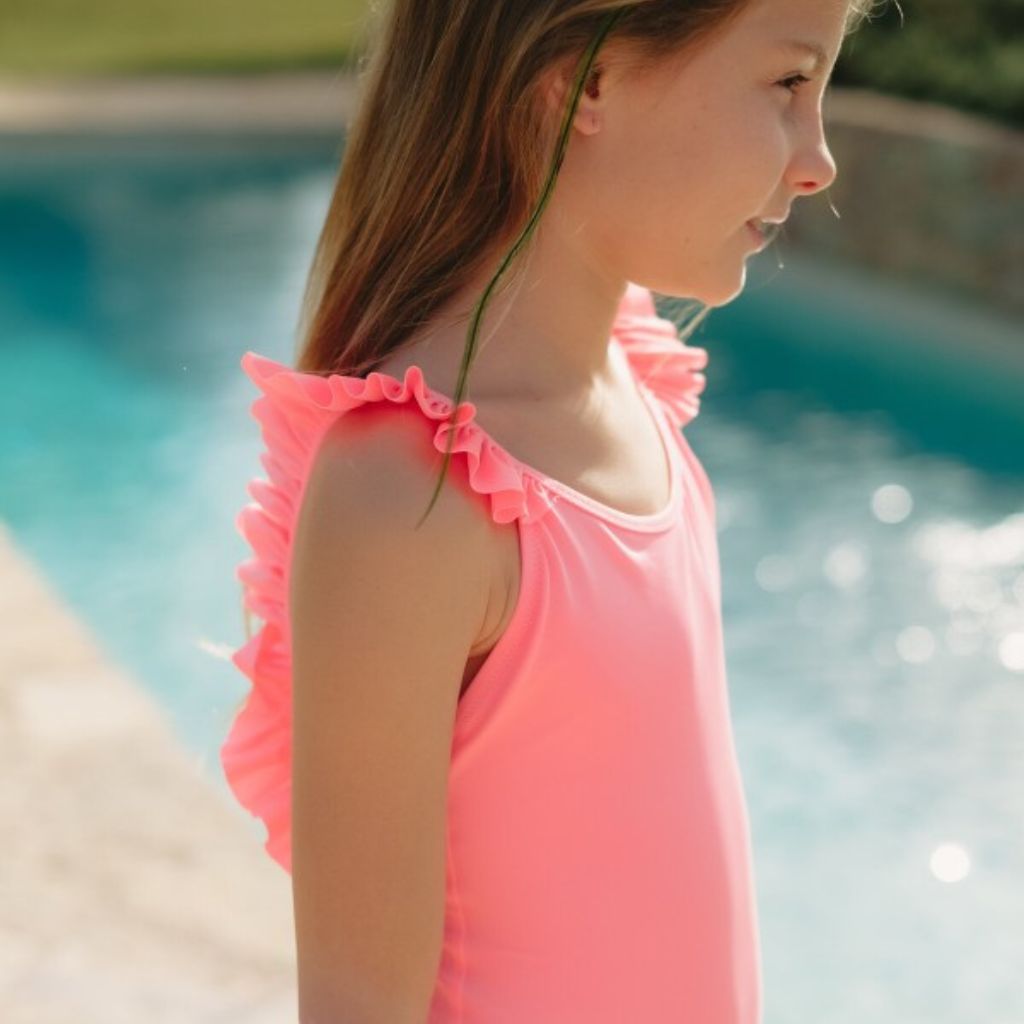 Little girl from the side wearing Lison Paris Bora Bora Swimsuit in Fluo Pink