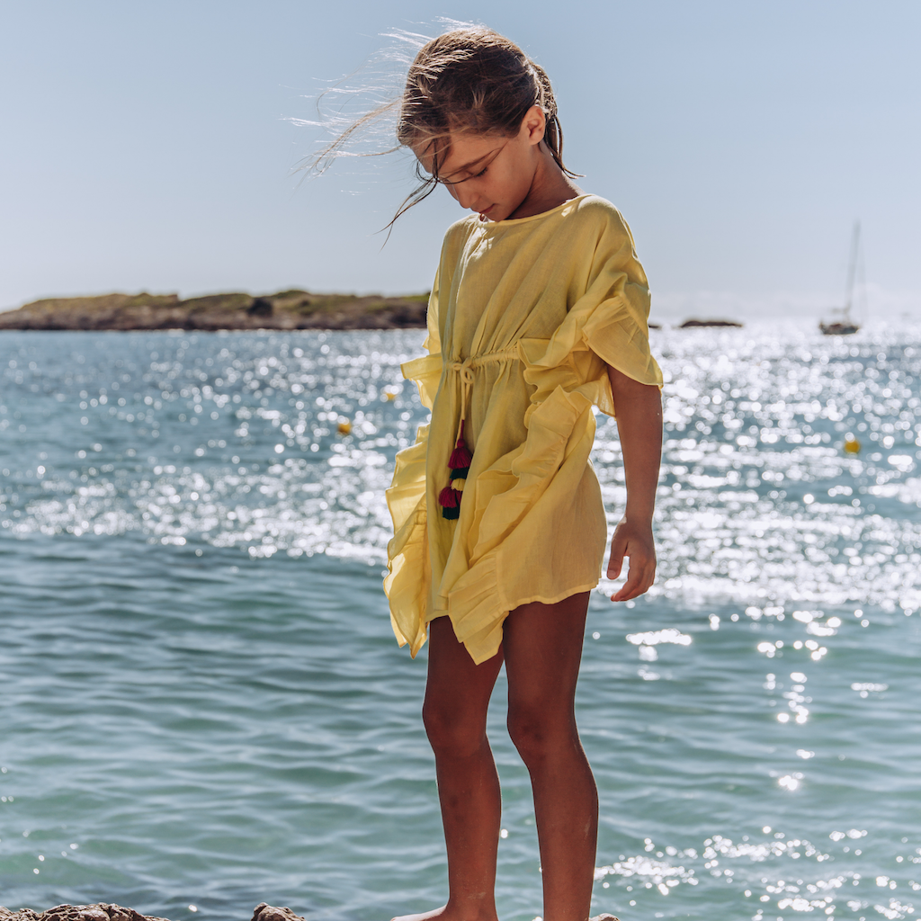 Little girl by the sea wearing Lison Paris Lea Poncho kaftan in Yellow