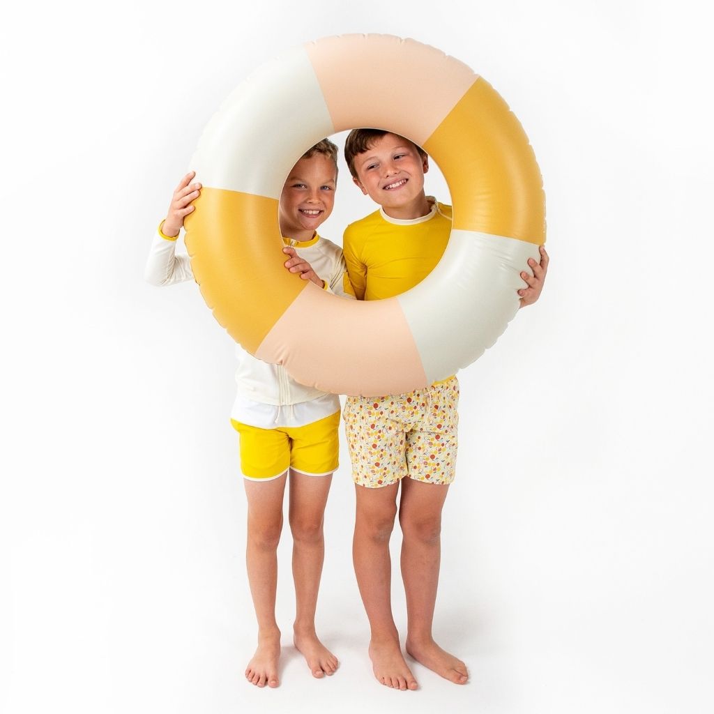 Two little boys wearing the Folpetto Jack swim shorts in Sicilian yellow and ivory