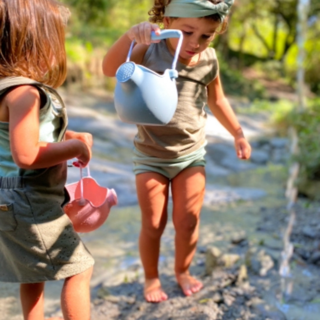 Children playing in the stream with their Scrunch silicone watering can in duck egg blue and old rose