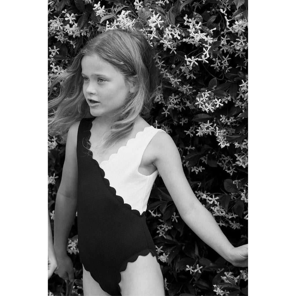 Little girl wearing the Marysia Bumby Canyon Point Swimsuit in Black and Coconut