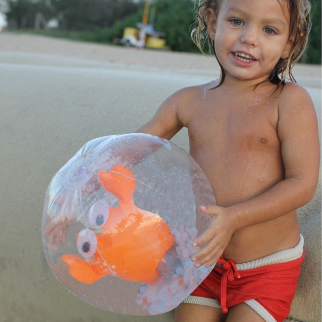 Little boy holding Sunnylife 3D inflatable beach ball in Sonny the Sea Creature Neon Orange