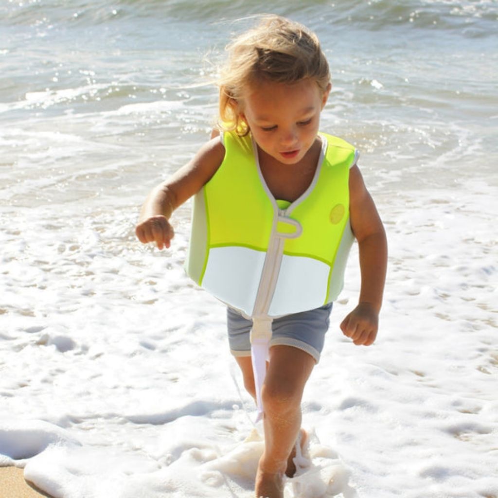 Little boy in the sea wearing Sunnylife Kids swim float vest EU design in Shark Tribe khaki