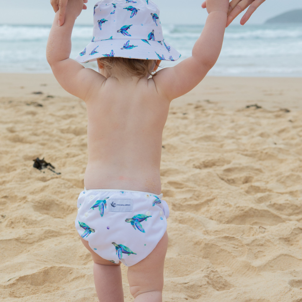 Little girl wearing Anchor & Arrow Sea Turtle print unisex reusable swim hat and swim nappy