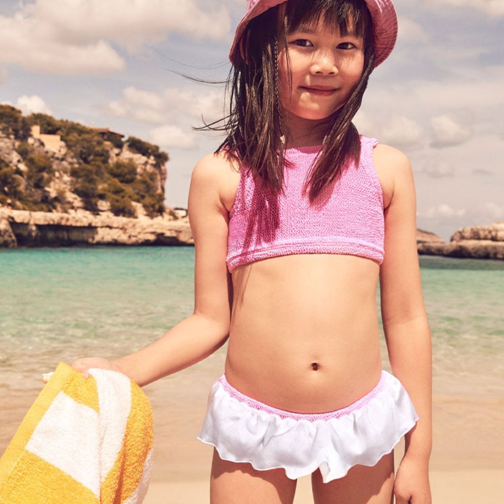 Little girl on the beach wearing the Hunza G Baby Olive Bikini in Bubblegum