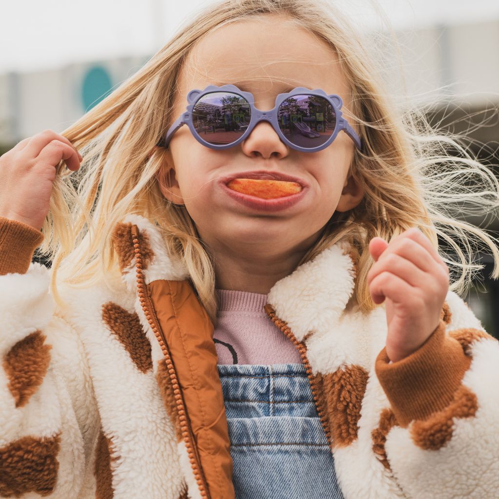 Little girl with apple in her mouth wearing the Ki et La Lion Sunglasses in Lilac