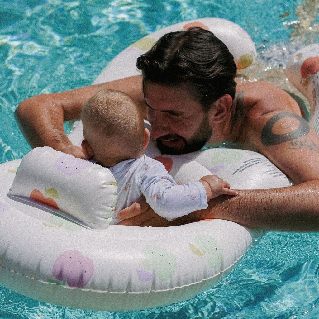 Dad and baby in the water using the Sunnylife Float Together Baby Seat in Apple Sorbet