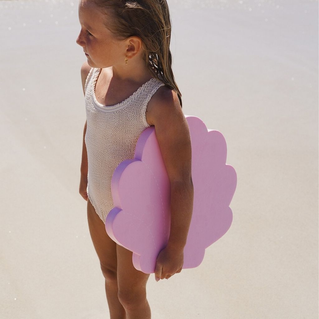 Little girl on the beach with the Sunnylife Kids Kickboard float in the Melody the Mermaid shape in pink under her arm