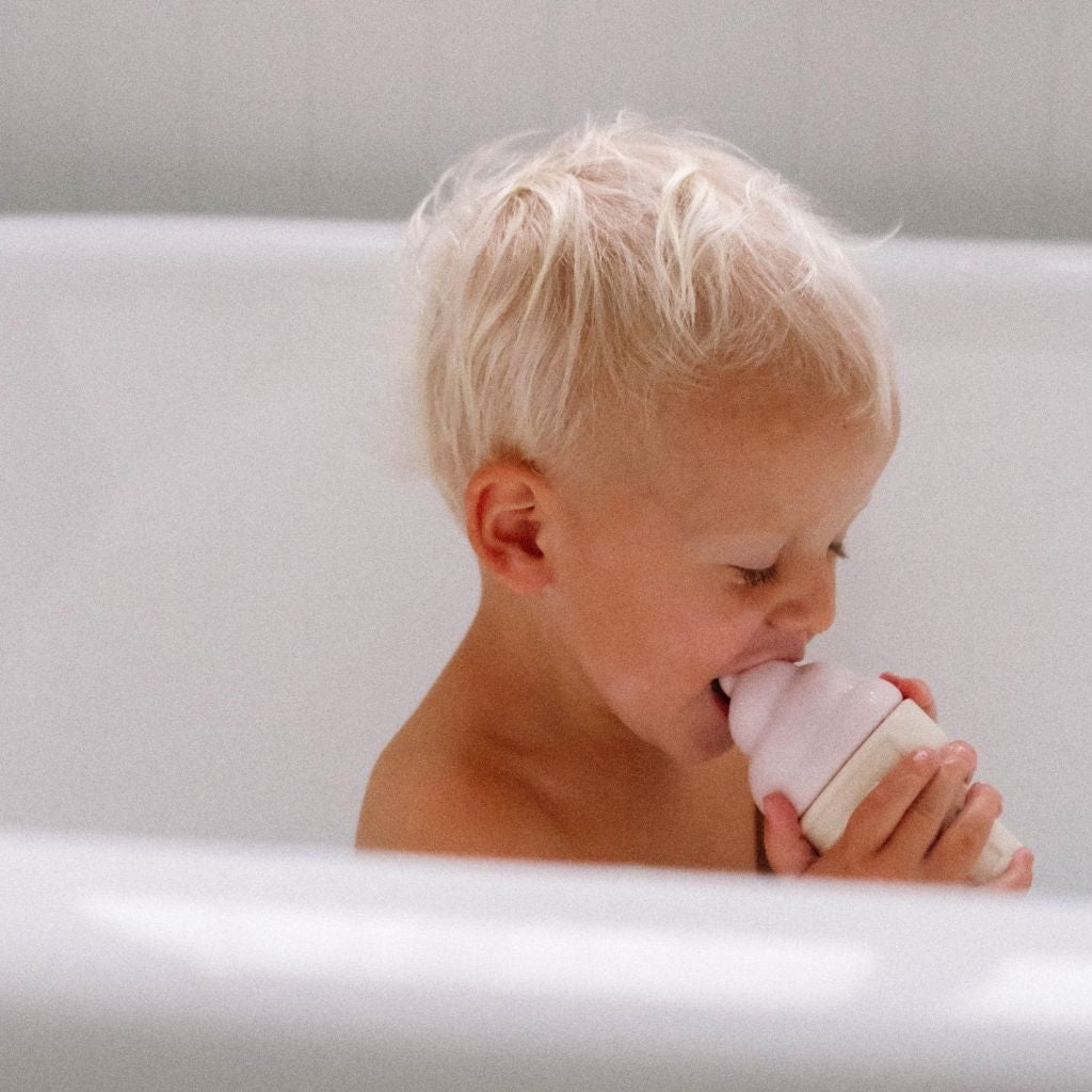 Little boy in the bath pretending to lick the Sunnylife Ice Cream Splash Toys in Apple Sorbet