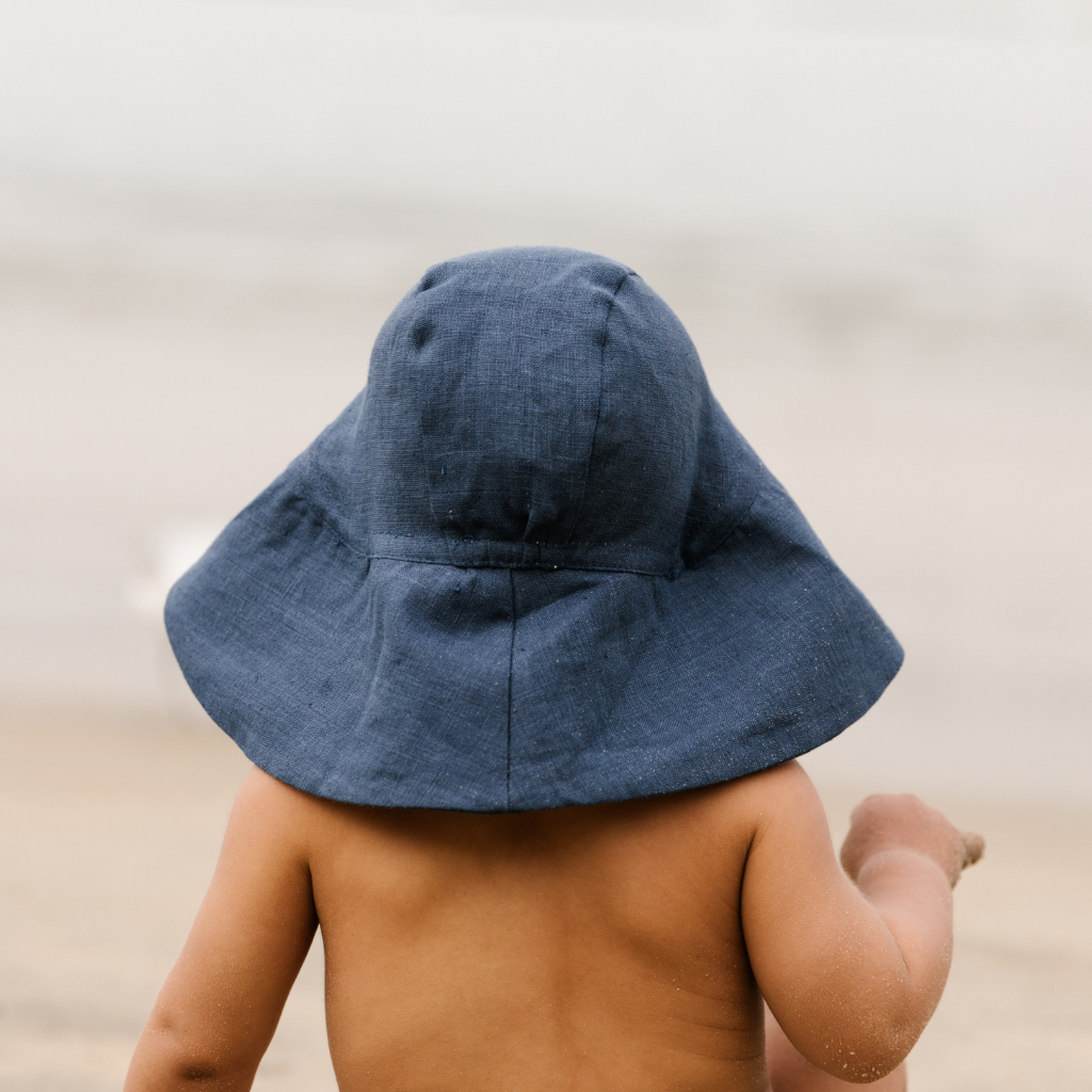 Little boy showing the back view of the Briar Baby sun hat in navy blue Cove