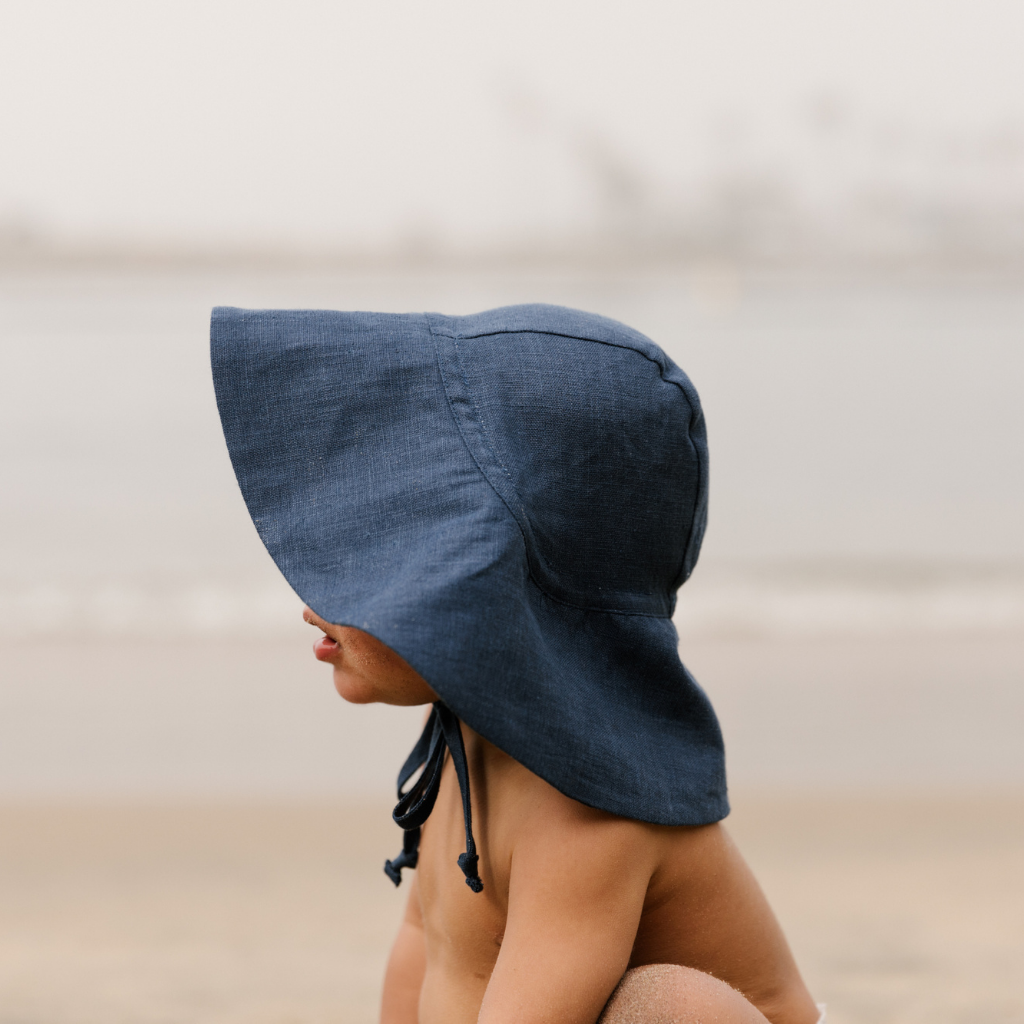 Little boy showing close up view of the side of the Briar Baby sun hat in navy blue Cove