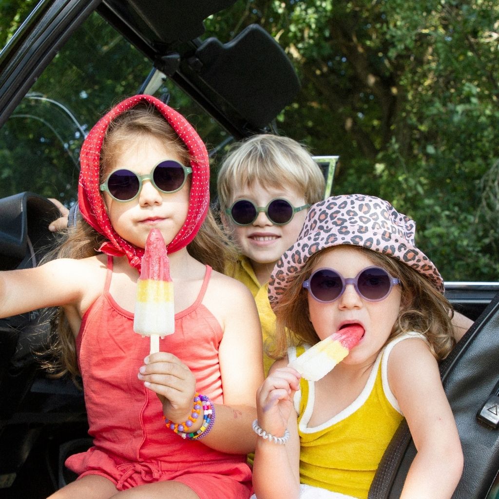 Children eating lollies and wearing Ki et La Woam round sunglasses in Purple and Bottle Green