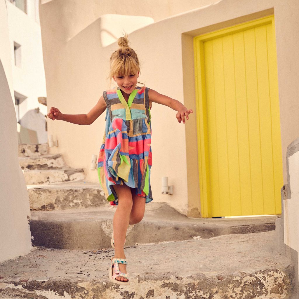 Little girl running down steps wearing the  Devotion Twins Stars Esmeralda dress for girls in blue and pink