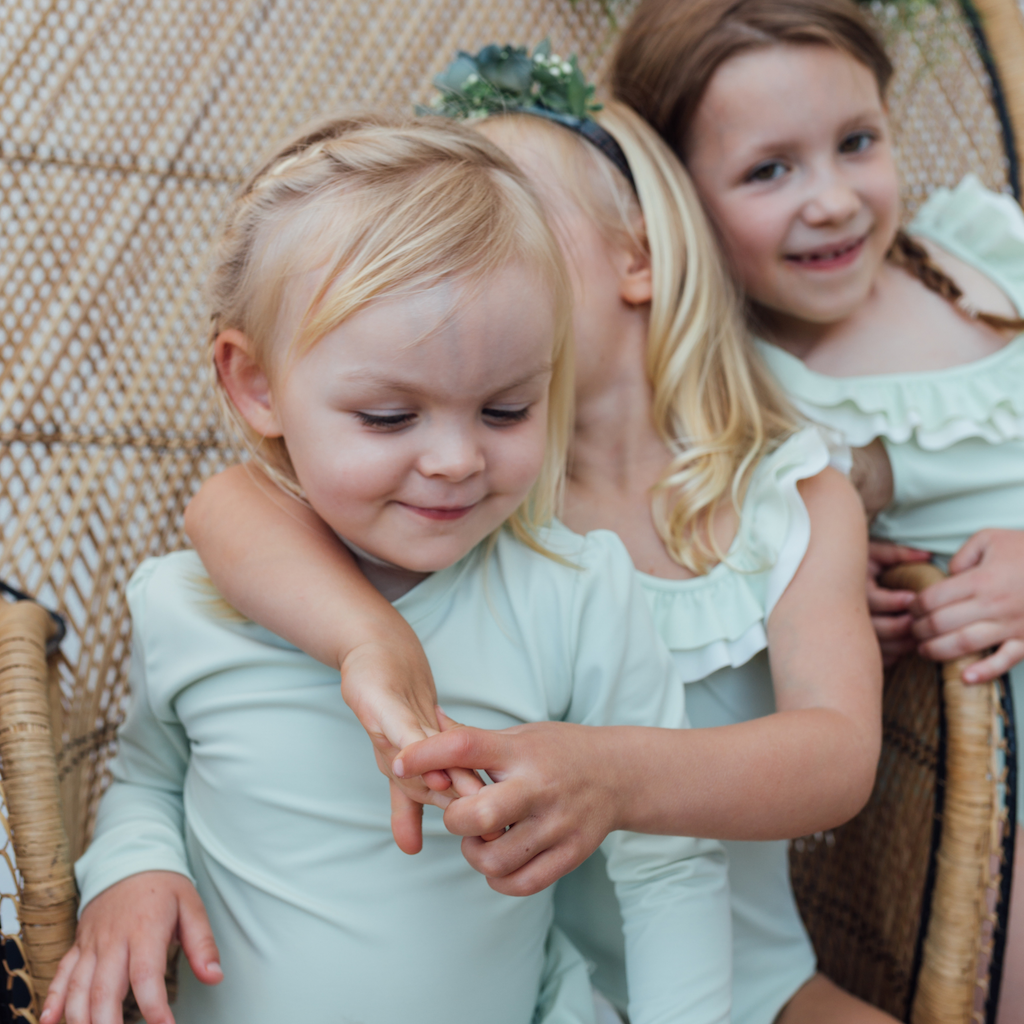 Girls wearing Folpetto Lucie rash guard cover up for girls in delicate mint green with white ruffle