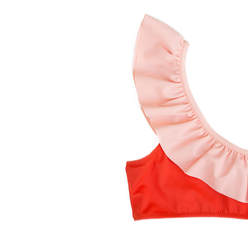Close up of Folpetto Maia one shouldered bikini for girls in mandarin red with peach pink ruffle