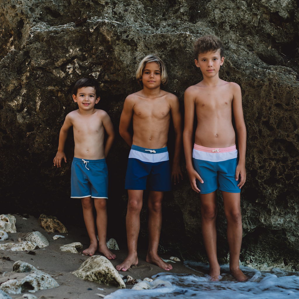 Boys wearing Folpetto swim shorts in shades of blue