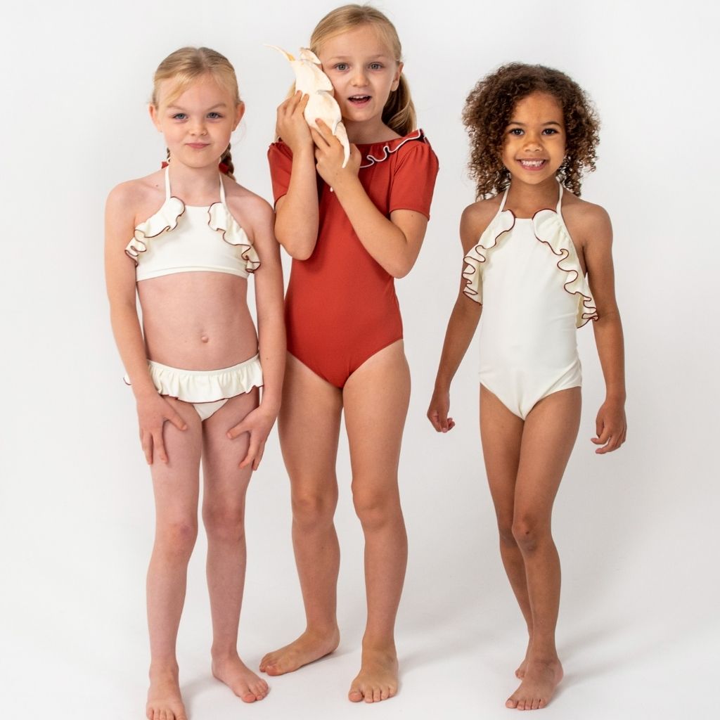 Little girls wearing Folpetto SS'22 swimwear including Leila Bikini and Linda swimsuit in ivory and terracotta