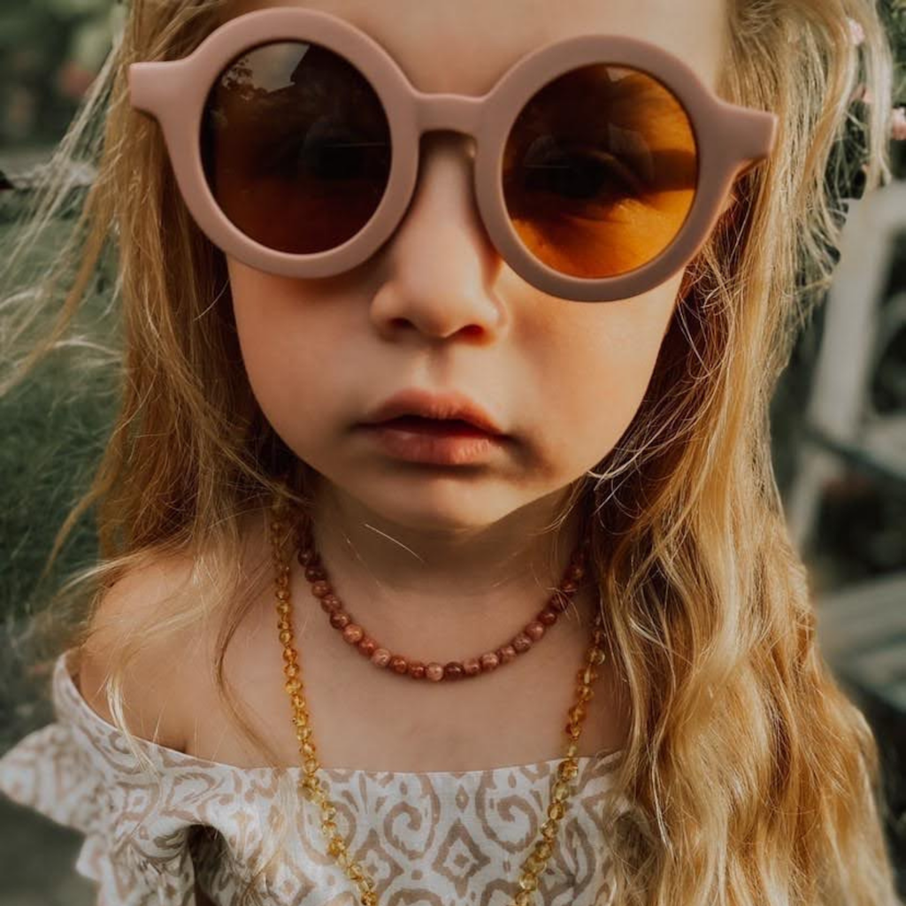 Girl wearing Grech & Co children's sunglasses in burlwood mauve with uv400 protection
