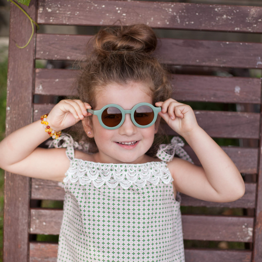 Girl wearing Grech & Co children's sunglasses in fern green with uv400 protection