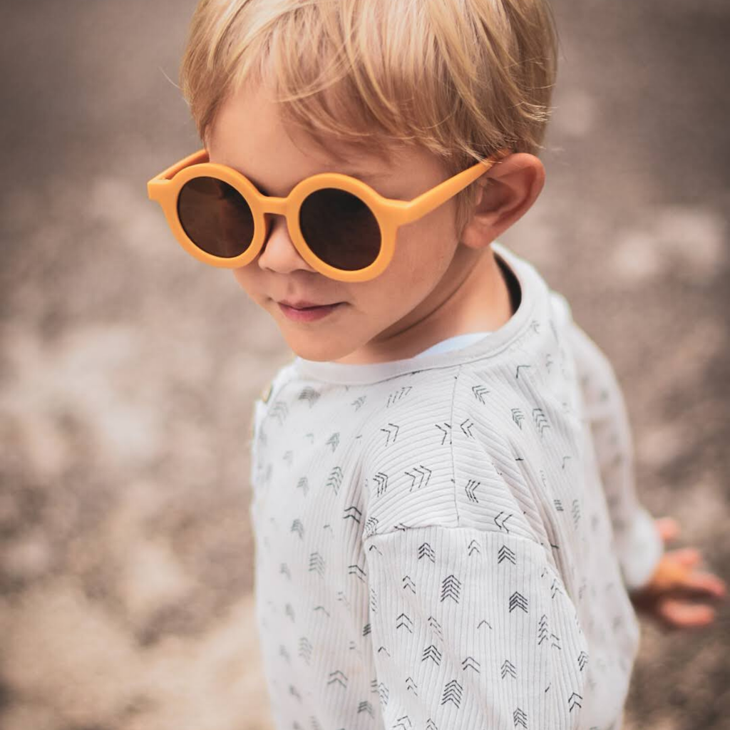 Little boy wearing Grech & Co children's sunglasses in golden orange with uv400 protection