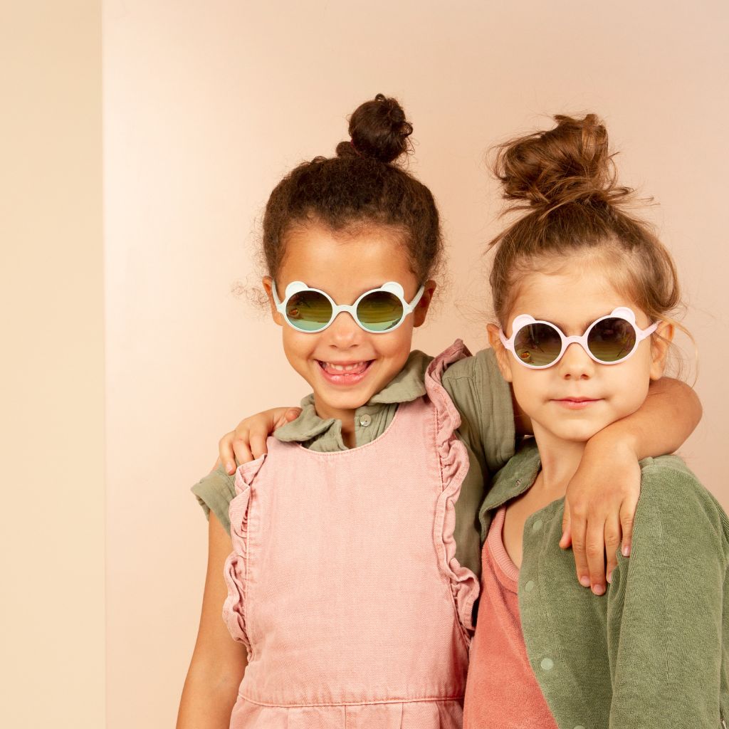 Little girls wearing Ki et La children's Ours'on teddy bear sunglasses in light pink and almond green