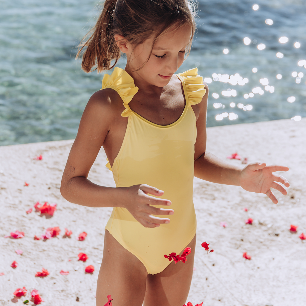 Little girl wearing the Lison Paris Bora Bora swimsuit with ruffles in yellow