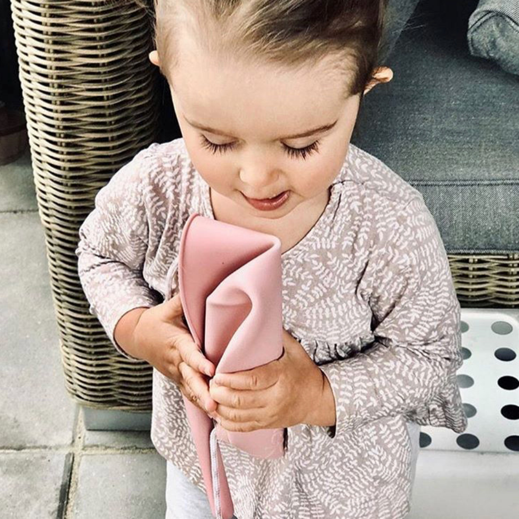 Little girl holding a scrunched up Scrunch silicone foldable frisbee flyer in old rose