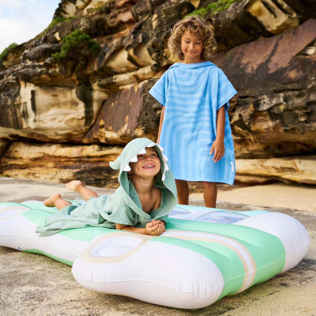 Little boy lying on an inflatable wearing his Sunnylife monster beach hooded robe