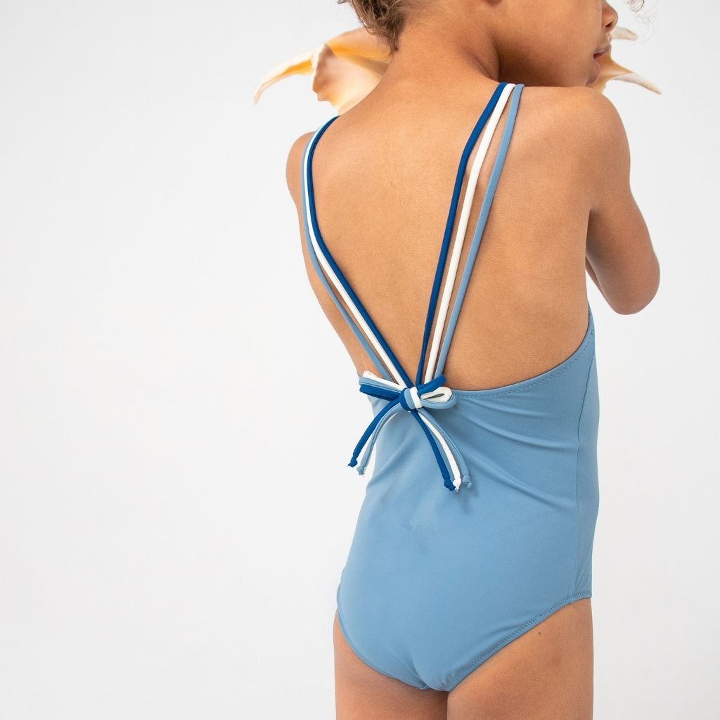 Little girl wearing the Folpetto Frida one piece swimsuit in dusty blue, midnight and ivory