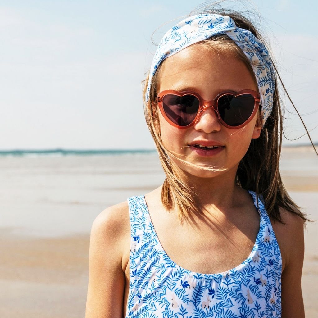Little girl not he beach wearing Maison Juli Margot orange crystal sunglasses