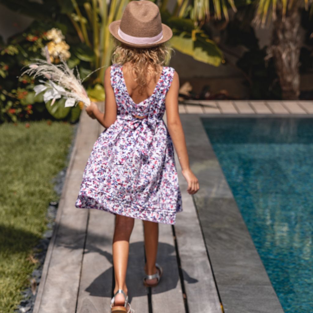 Little girl walking by the pool wearing the Poupette St Barth Kids Amelie Mini Dress in Blue Blueberry Print