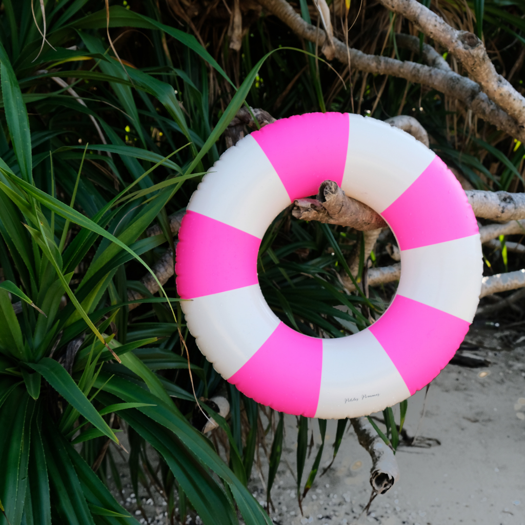 Petites Pommes striped inflatable rubber ring in pink flamingo hanging on a tree