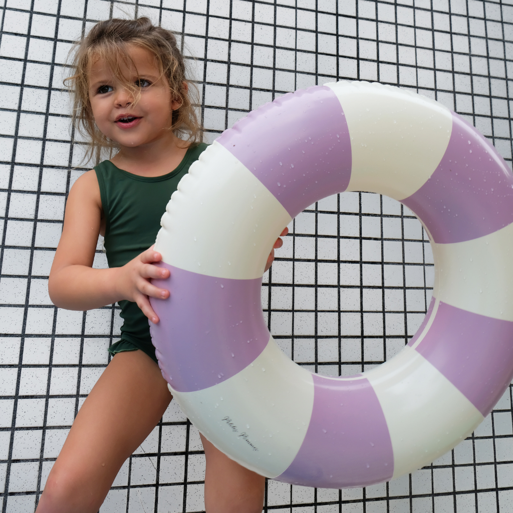 Little girl holding Petites Pommes rubber ring striped inflatable in violet purple