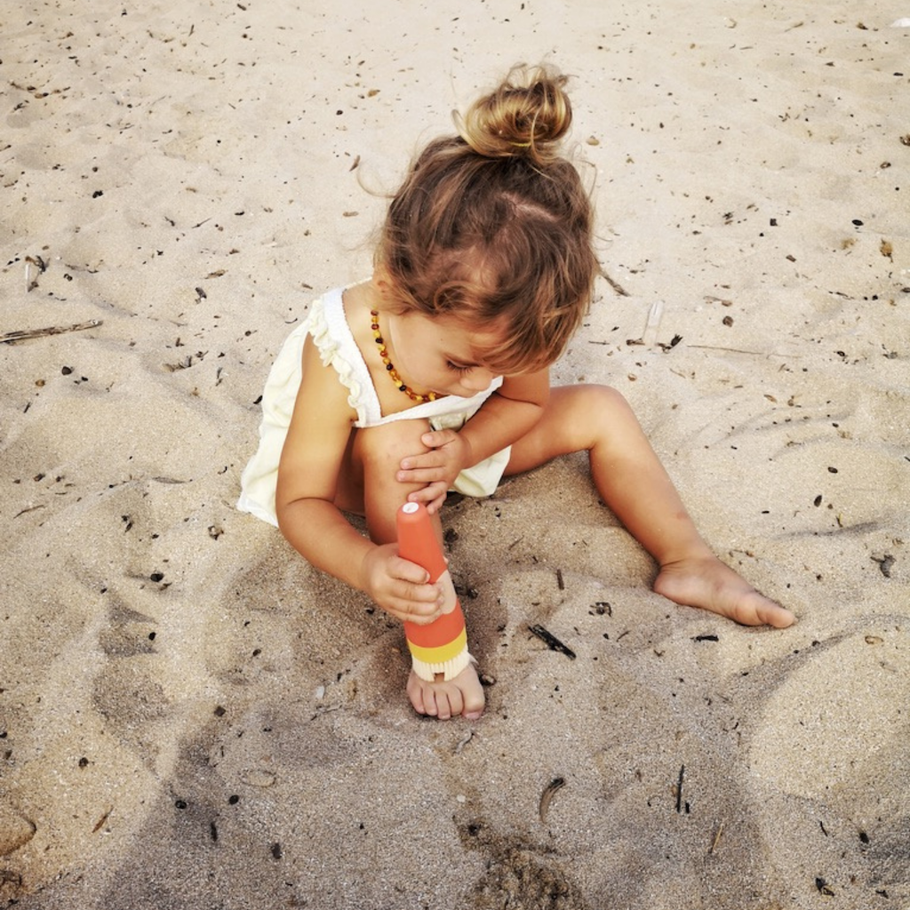 Girl on beach using beach essential SavviSand Sand Removal applicator 