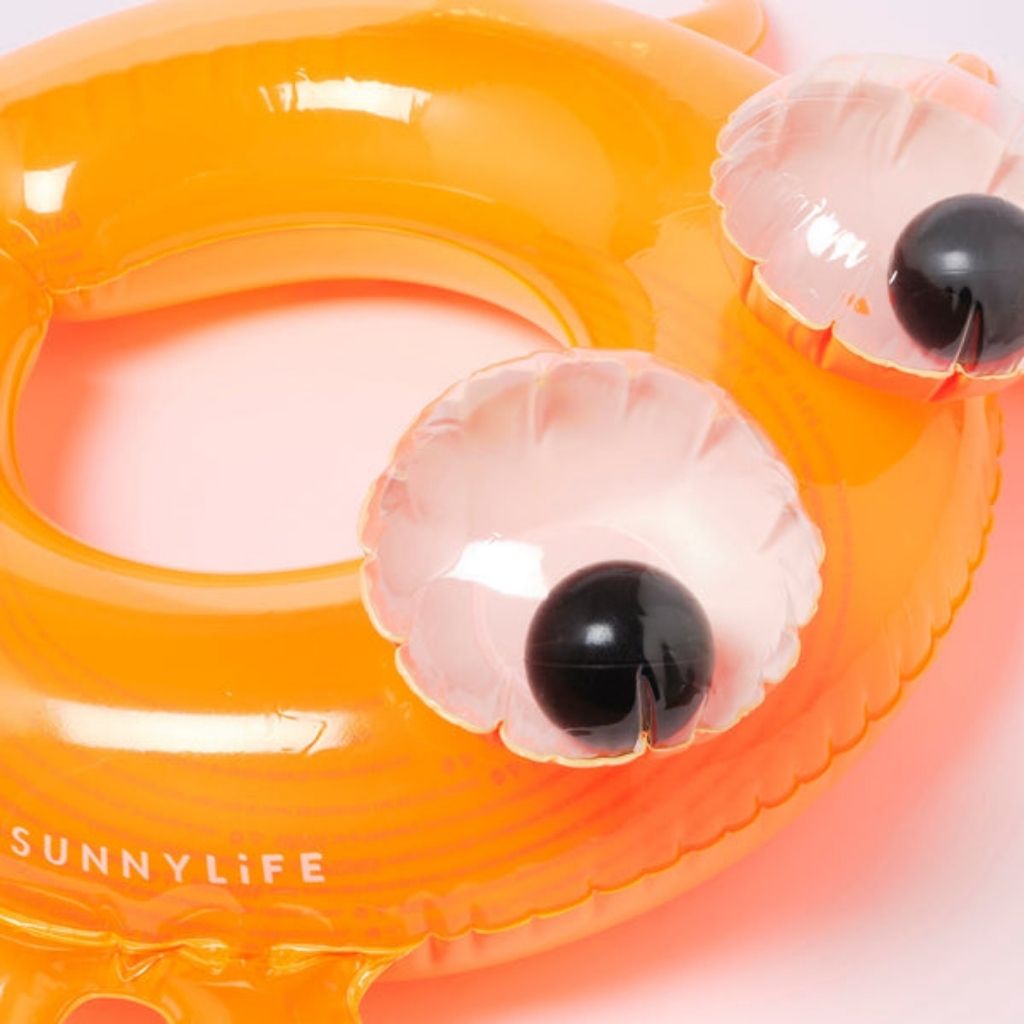 Close up of the googly eyes on the Sunnylife kiddy pool ring in sonny the sea creature neon orange
