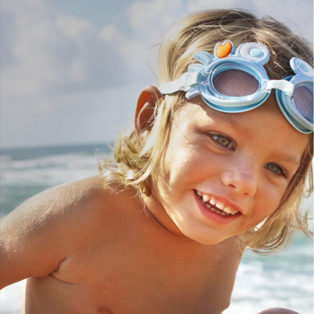 Little boy wearing Sunnylife Kids mini swim goggles in sonny the sea creature neon orange