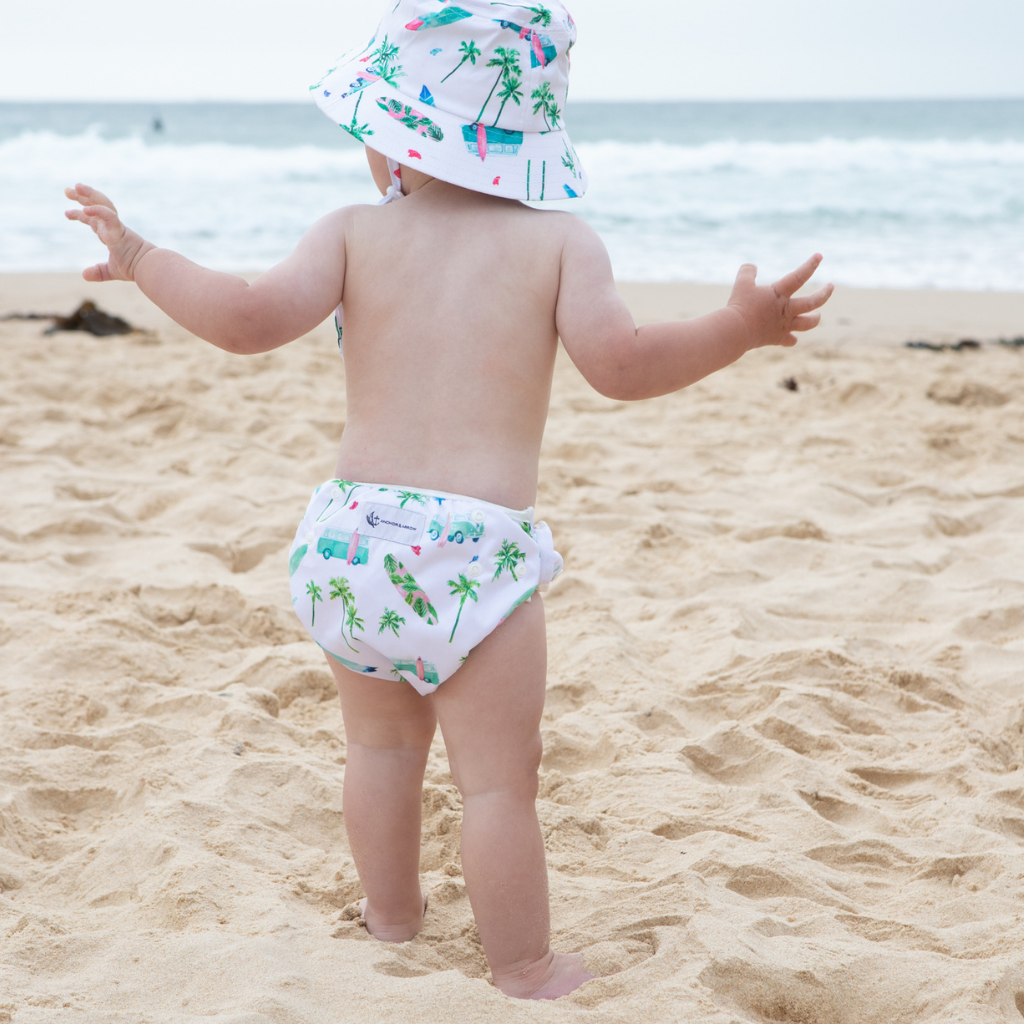 Baby on the beach wearing Anchor & Arrow Chasing Waves print unisex reusable swim nappy