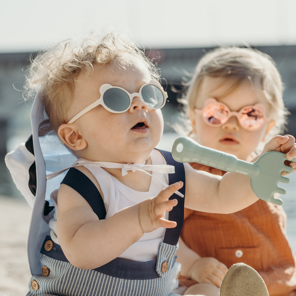 Two toddlers wearing Ki et La Ourson teddy bear sunglasses for children 1 - 4 years in white and peach