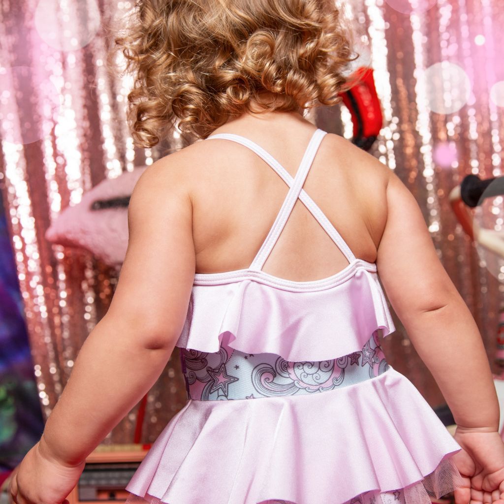 Little toddler girl from the back wearing the Tutu Du Monde Bébé Falling Star swim suit in Star Waves print showcasing the cross back straps